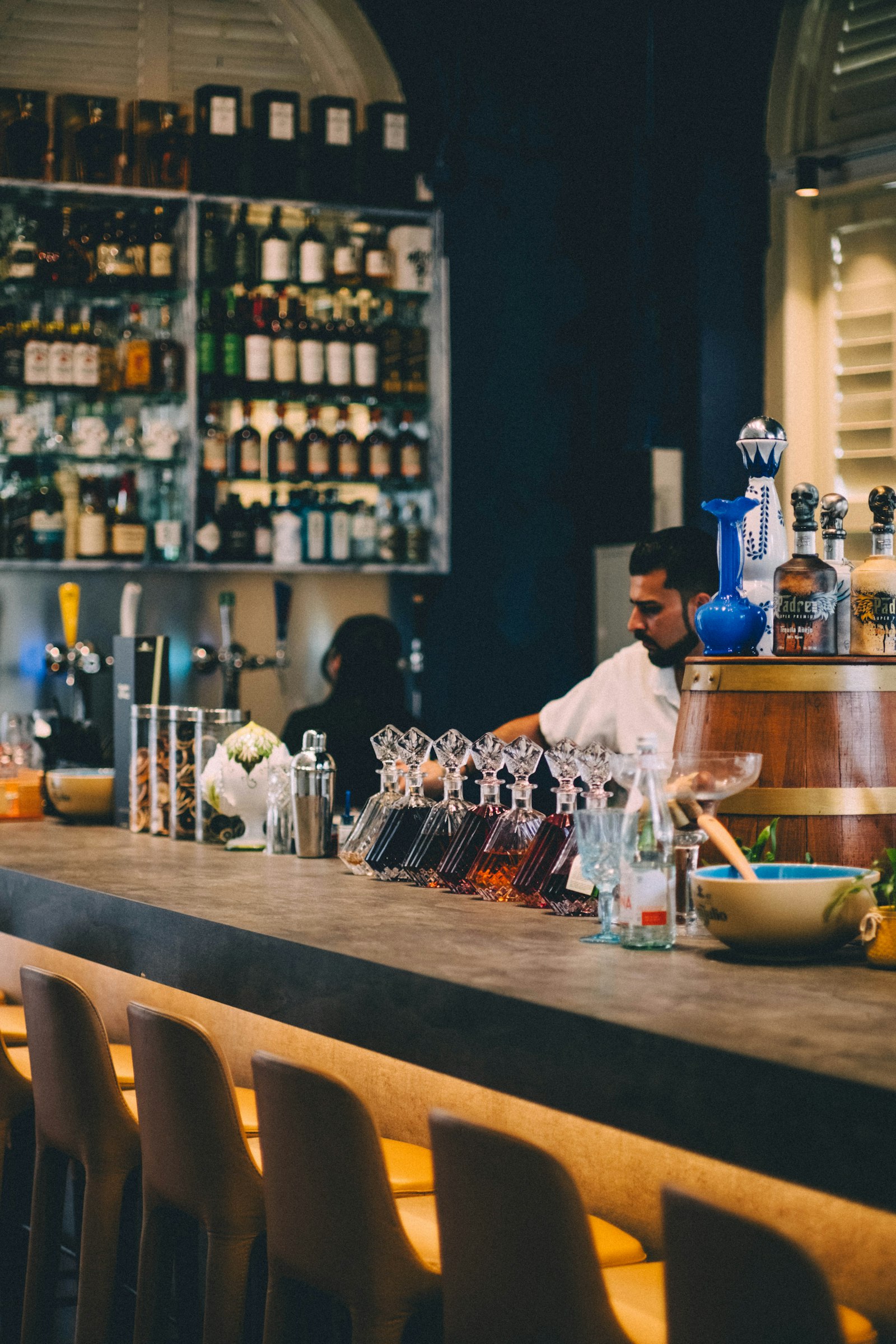 A bartender preparing drinks behind the bar counter, learning the craft on the job